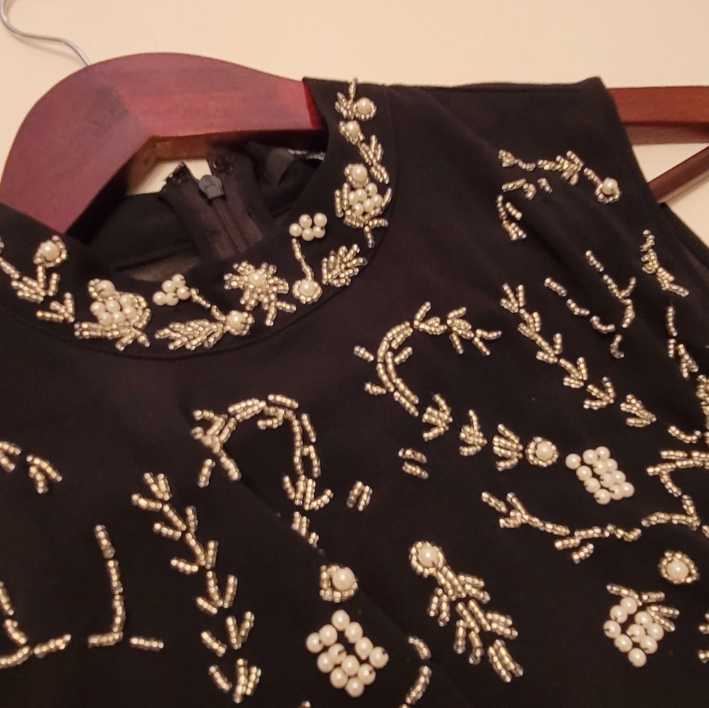 Black top with white embellishments and pearls